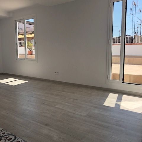 Interior Espacio interior vacío con luz natural y ventanas grandes. Suelo de madera clara.