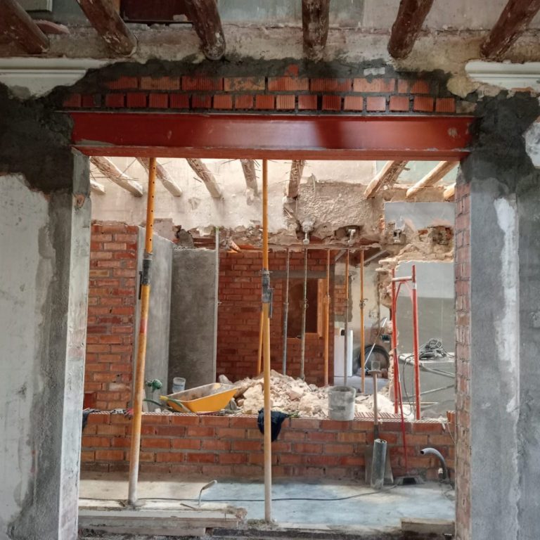 Rehabilitación Apertura en una pared con vigas de soporte. Fondo de obra con ladrillos y materiales de construcción.