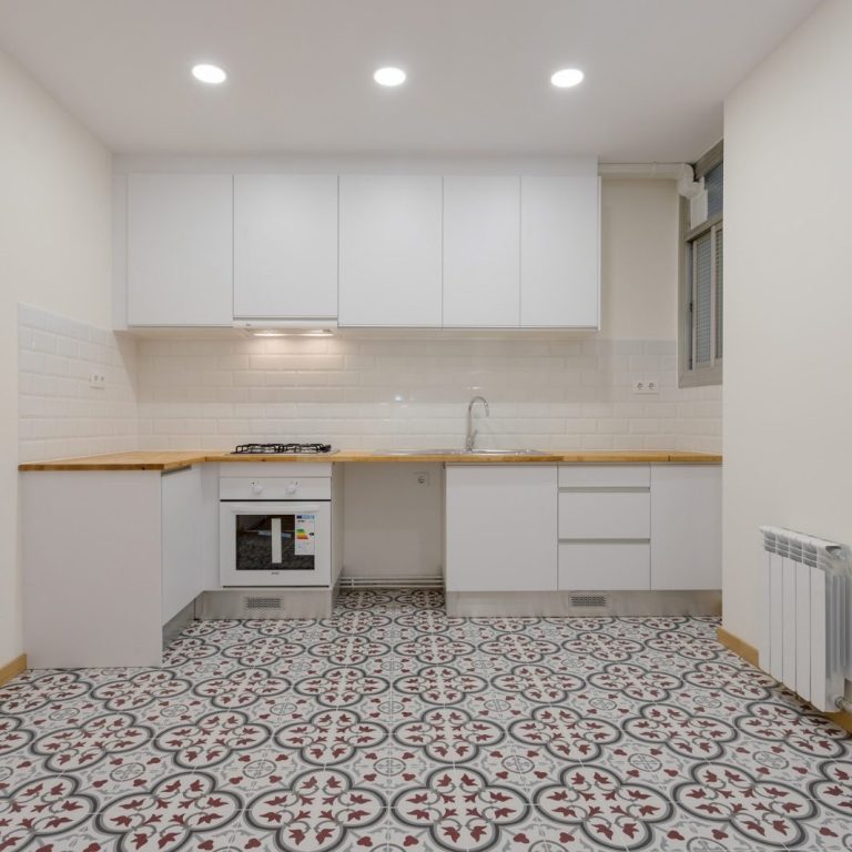Cocina Cocina moderna con azulejos decorativos, muebles blancos y encimera de madera.